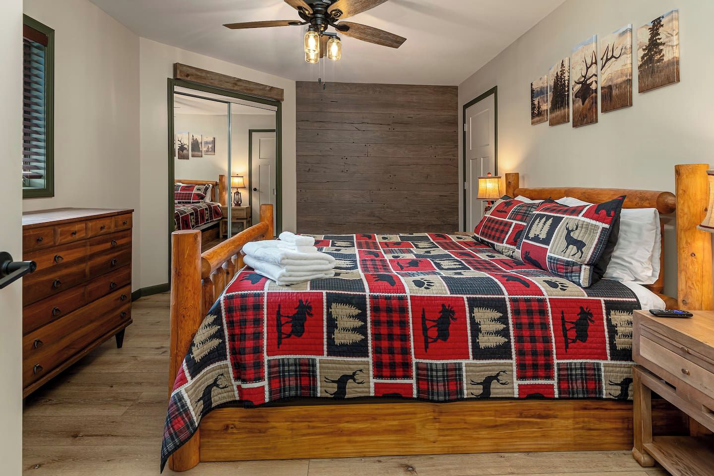 Een slaapkamer met een houten bed, een kapstok, een spiegel en een plafondventilator.