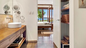 A modern bathroom with a wooden vanity, two round mirrors, a white sink, and a towel rack.