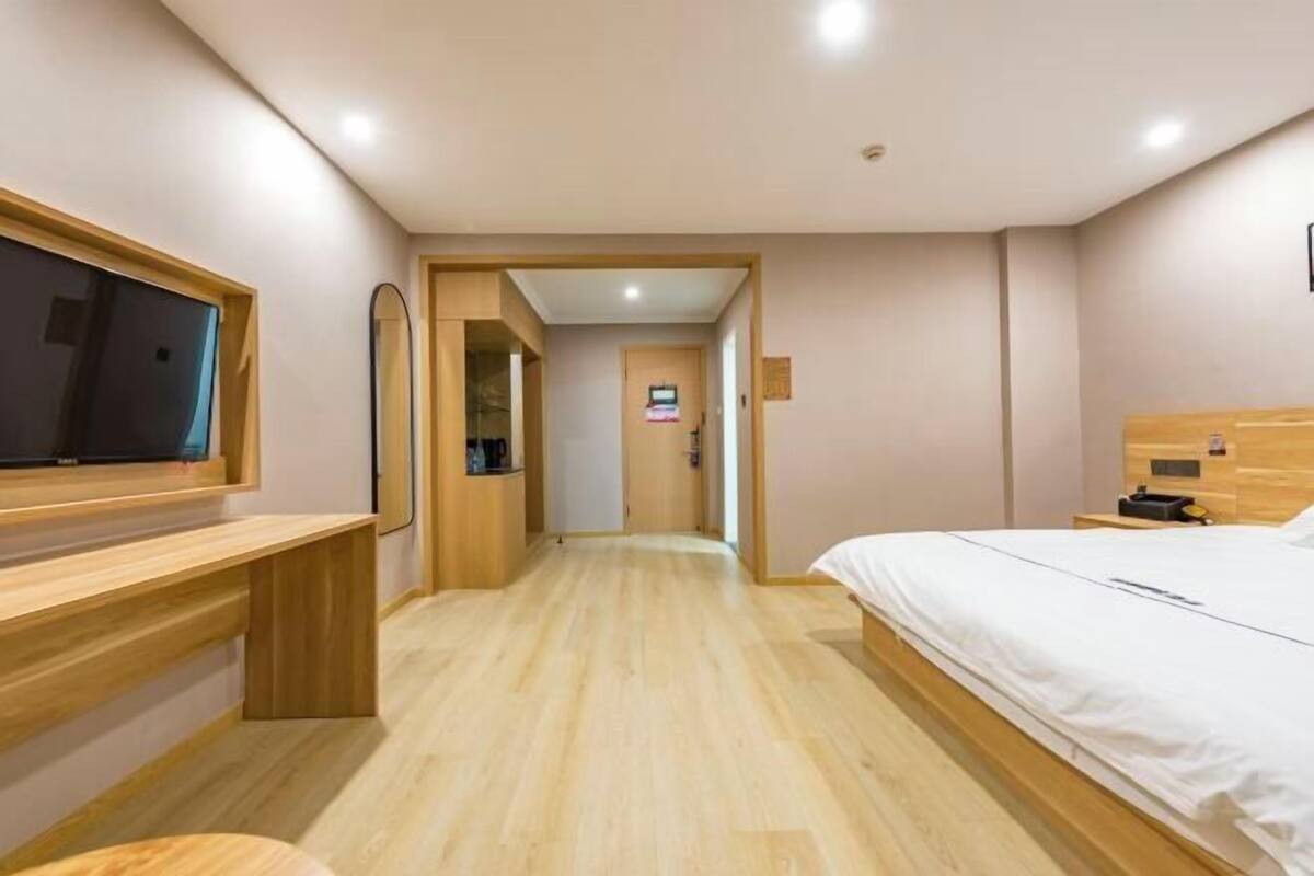 Hotellihuoneessa on puinen työpöytä, sänky ja seinälle asennettu televisio.