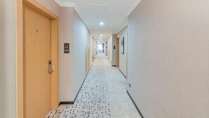 A hotel hallway with a patterned floor, wooden doors, and a sign indicating the direction to the elevator. - Qiha Hotel (Xiangshan North Gate Qingcao Alley) (Xiangshan)