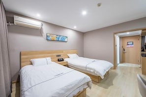 A hotel room with two beds, a wooden headboard, an air conditioning unit, a nightstand, and a painting on the wall. - Qiha Hotel (Xiangshan North Gate Qingcao Alley) (Xiangshan)