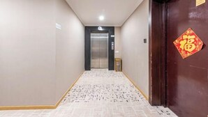 A hallway with a patterned floor leading to an elevator. - Qiha Hotel (Xiangshan North Gate Qingcao Alley) (Xiangshan)