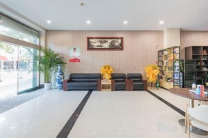 Un hall de hotel con una recepción, zona de estar y una estantería.