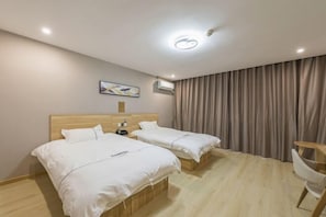 A hotel room with two beds, a wooden headboard, a desk, a chair, a painting on the wall, and a window with curtains. - Qiha Hotel (Xiangshan North Gate Qingcao Alley) (Xiangshan)