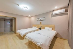 A hotel room with two beds, a wooden headboard, an air conditioning unit, a painting on the wall, and a door leading to another room. - Qiha Hotel (Xiangshan North Gate Qingcao Alley) (Xiangshan)