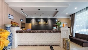 A hotel reception area with a marble counter, a large window with curtains, and a reception desk with a sign that reads "XIHA HOTEL". - Qiha Hotel (Xiangshan North Gate Qingcao Alley) (Xiangshan)