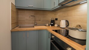 A modern kitchen with light blue cabinets, a wooden countertop, a stainless steel sink, a kettle, a coffee maker, and a rice cooker. - Little Gem by Corfu Escapes (Corfu)