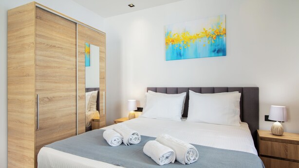 A hotel room with a large bed, a wardrobe, a painting, and a nightstand with a lamp. - Little Gem by Corfu Escapes (Corfu)