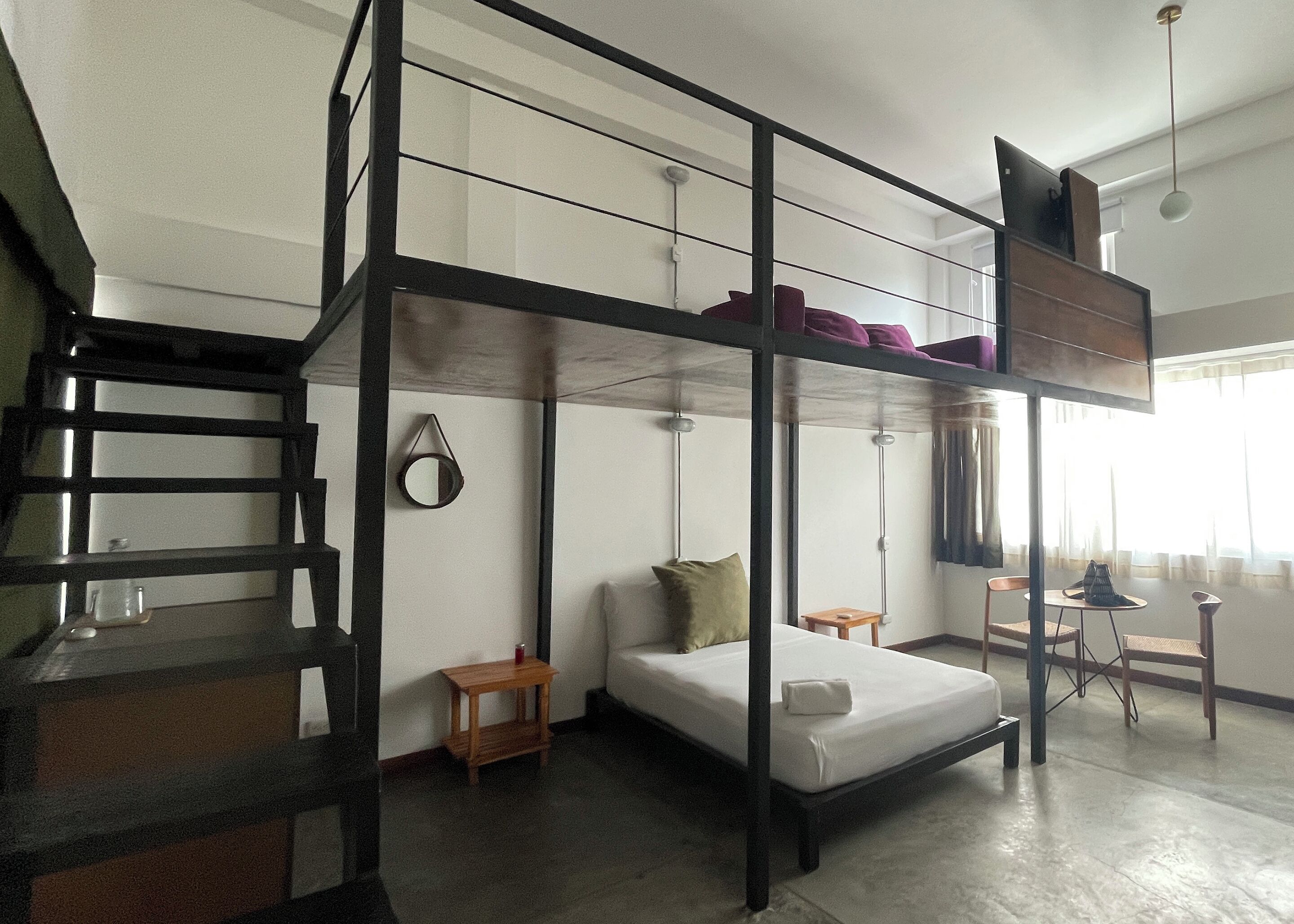 A bunk bed room with a wooden ladder, a small table, and a chair.