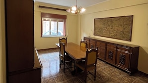 A dining area with a wooden table and chairs, a chandelier, a cabinet, and a large painting on the wall. - Uncle Peppino Holiday House (Torregrotta)