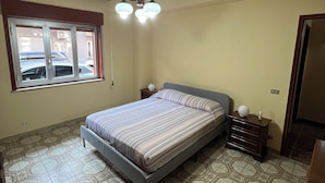 A bedroom with a bed, a window, a ceiling fan, and patterned floor tiles. - Uncle Peppino Holiday House (Torregrotta)