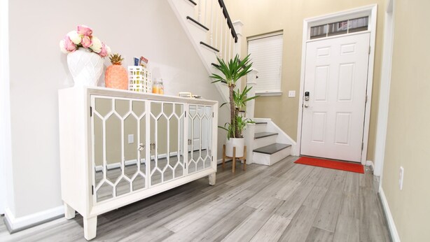A hallway with a white console table, a potted plant, a staircase, and a door.