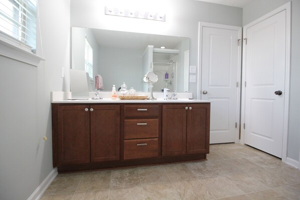 Un baño con tocador de madera, un espejo grande y una puerta blanca.