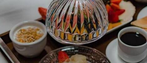 A breakfast tray with a glass dome cover, a cup of coffee, a glass of orange juice, and a plate with food.