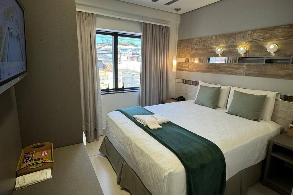 Habitació d'hotel moderna amb un llit gran, un escriptori i vista exterior.