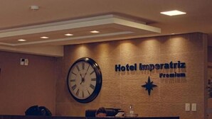 A hotel reception desk with a clock and a sign that reads "Hotel Imperatriz Premium". - Hotel Imperatriz Premium (Telemaco Borba)