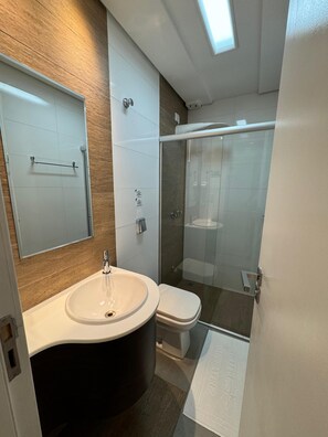 A modern bathroom with a large mirror, a sink, a toilet, and a glass-enclosed shower. - Hotel Imperatriz Premium (Telemaco Borba)