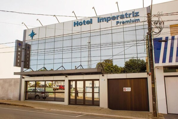 Hotel Imperatriz Premium with a modern glass facade, a prominent star logo, and a visible entrance with a parking area in front. - Hotel Imperatriz Premium (Telemaco Borba)