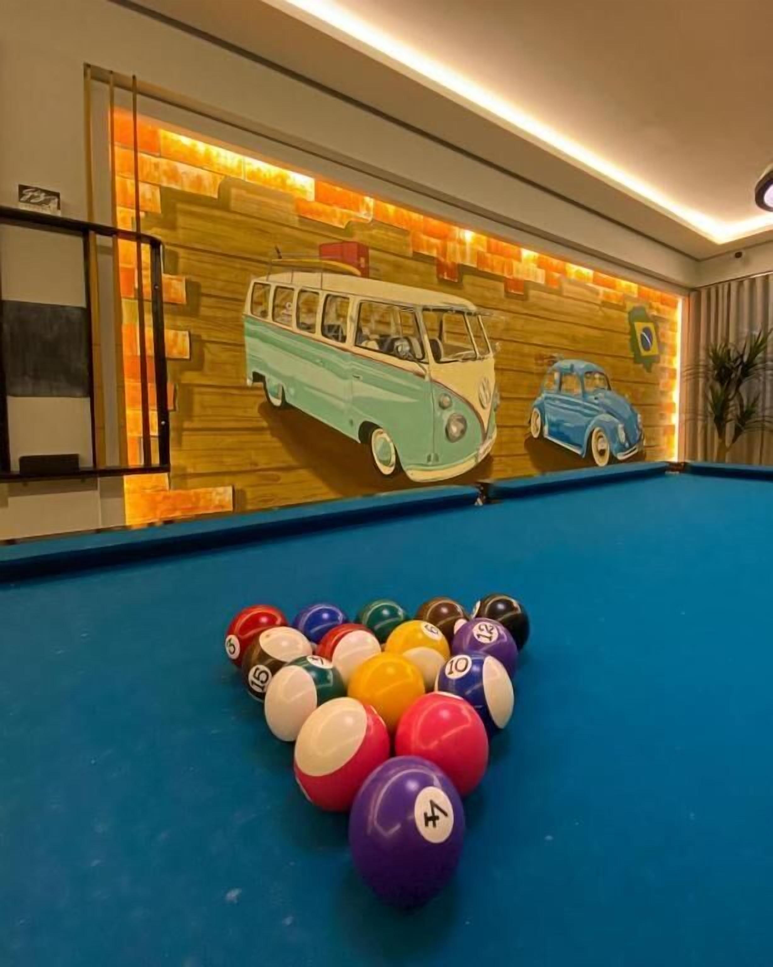Un biliardo con palle colorate e un murale raffigurante auto d'epoca sullo sfondo.