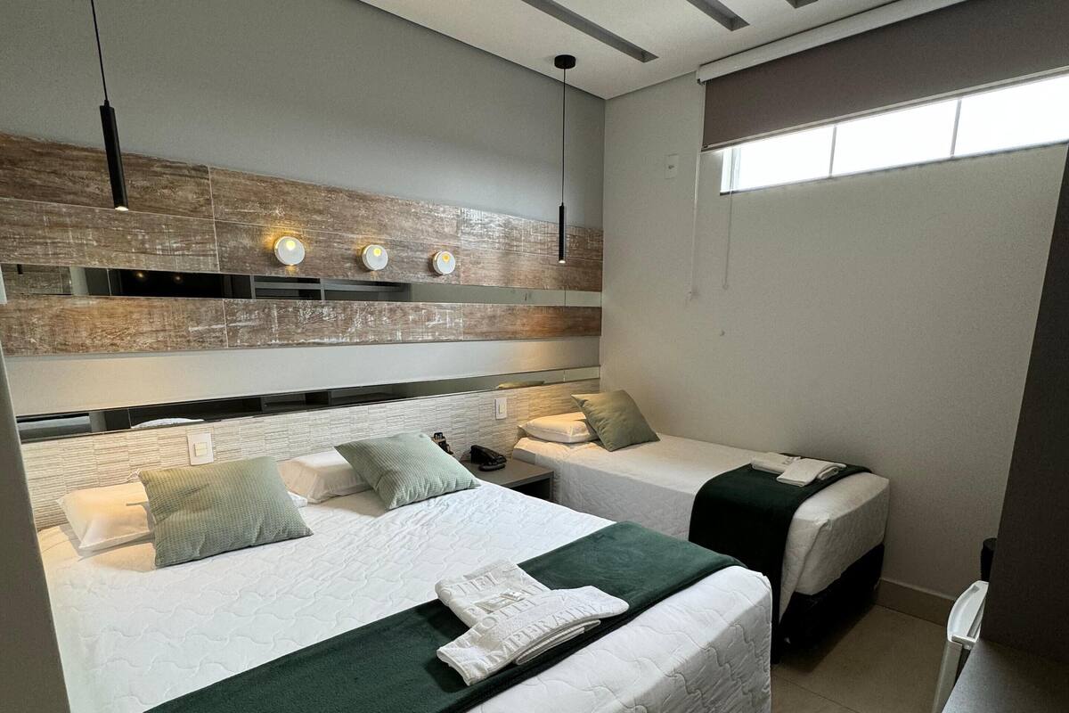 Habitació d'hotel moderna amb dos llits, una finestra gran i una cadira incorporada.