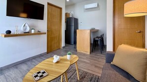 A modern living room with a sofa, a wooden coffee table, and a TV mounted on the wall. - Condo a 3 blocks from La Paz Malecon (La Paz)