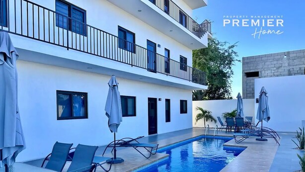 A modern building with a swimming pool, outdoor seating, and a balcony. - Condo a 3 blocks from La Paz Malecon (La Paz)