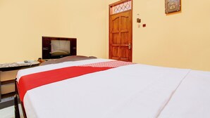 A hotel room with a bed, a television, a wooden door, and a wall-mounted light fixture. - Hotel O Griya Mustika Syariah (Ngemplak)
