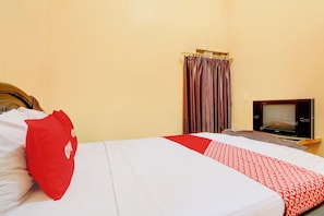 Una camera d'albergo con un letto, una televisione e una tenda.