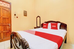 Un letto rifatto con una coperta rossa e bianca e due cuscini con la scritta 'OYO'.