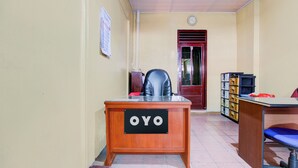 A room with a wooden desk labeled "OYO," a black office chair, a red door, and a filing cabinet with multiple drawers. - Hotel O Griya Mustika Syariah (Ngemplak)
