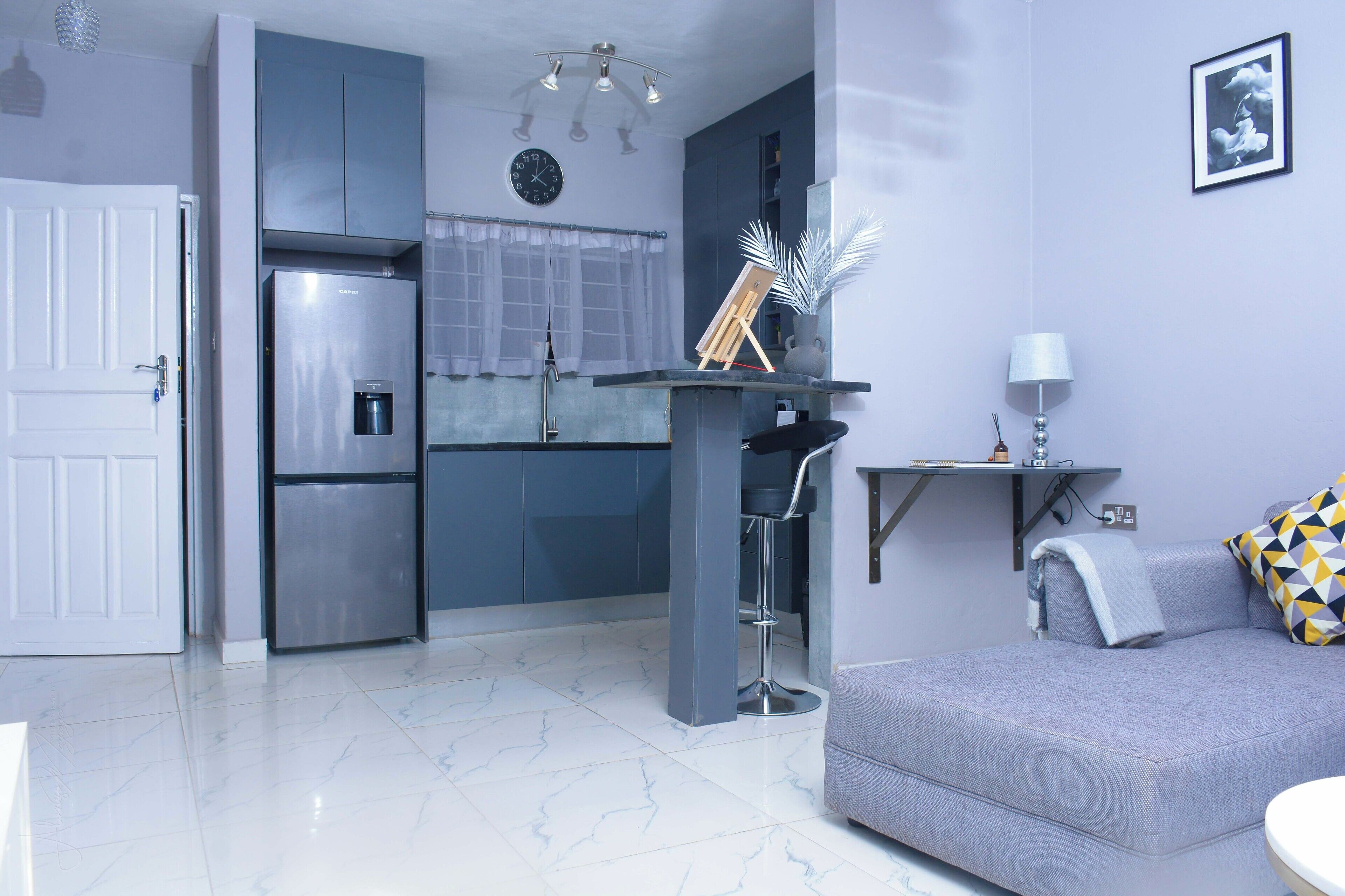 Una cocina moderna con refrigerador, pileta y comedor con sofá y una mesita.