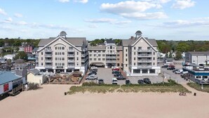 Een hotel aan de kust met meerdere verdiepingen, een parkeerplaats en uitzicht op het strand.