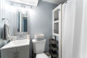 A bathroom with a white sink, a toilet, a mirror, and a shower curtain.