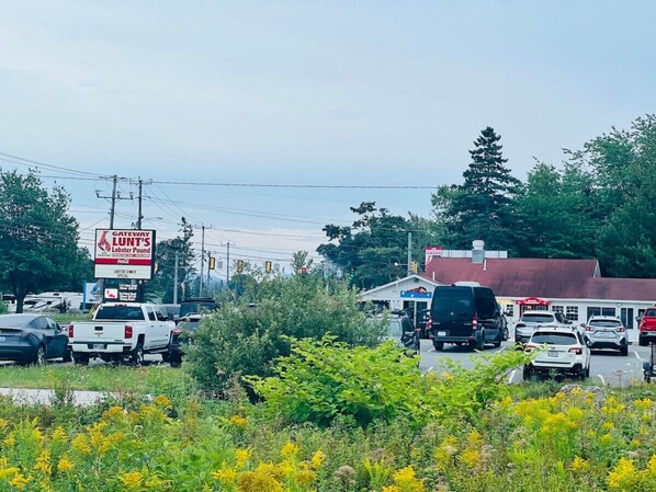 A busy street with multiple vehicles, a sign for Gateway Lunt's Lobster Pound, and a building with a red roof.