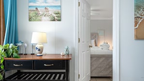 A hotel room with a wooden desk, a lamp, decorative items, and a beach-themed painting. - Cozy 1 BR Suite Steps to the Beach (469) (Old Orchard Beach)