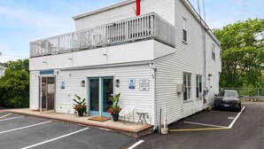A white building with a blue door, a sign reading "Laundromat," and a parking lot with a car. - Beachside Getaway | Walk to Pier & Downtown (463) (Old Orchard Beach)