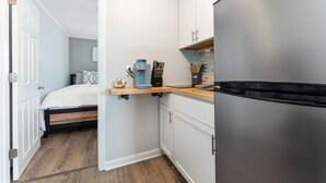A compact kitchen with a built-in refrigerator, a coffee maker, and a knife block on the countertop.