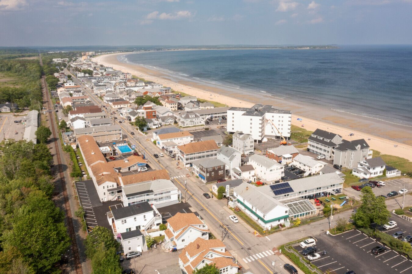 Vista aèria d'una ciutat costanera amb una platja, edificis residencials i un aparcament.
