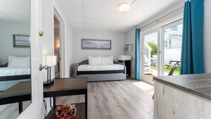 A bedroom with a bed, a desk, and a window with curtains.