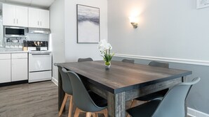 A modern kitchen with white cabinets, a stainless steel range hood, and a built-in oven.