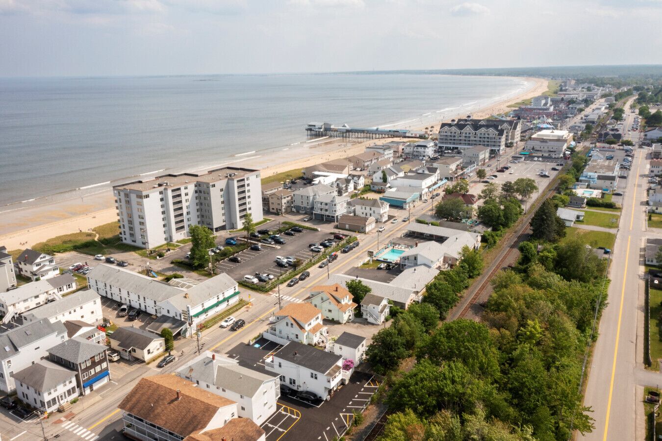 A coastal town with a beachfront, a parking lot, and various buildings including a multi-story hotel.