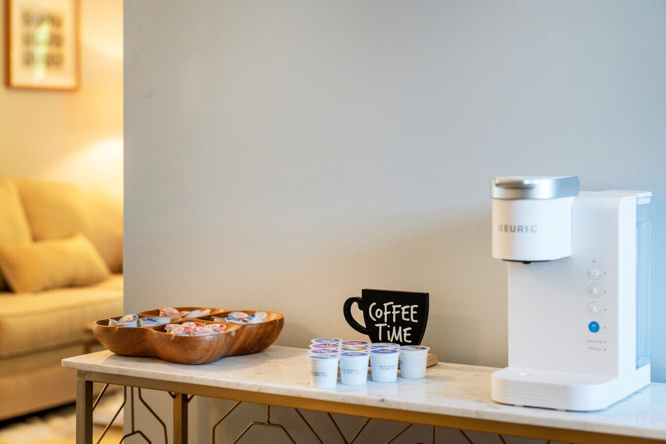 A coffee station with a Keurig machine, a sign that says "Coffee Time," and a wooden tray with coffee cups and lids.