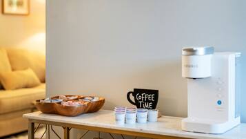 A coffee station with a Keurig machine, a sign that says "Coffee Time," and a wooden tray with coffee cups and lids.