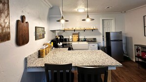 A kitchen with granite countertops, two pendant lights, a refrigerator, and a wooden cutting board on the wall. - 2br-newly Renovated Full Kitchen-3 Mins Asia Dist (Oklahoma City)