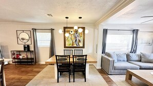 A modern living room with a dining area, featuring a wooden dining table, black chairs, a grey sofa, and a painting above the table. - 2br-newly Renovated Full Kitchen-3 Mins Asia Dist (Oklahoma City)