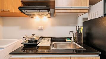 Una cocina con armarios de madera, encimera negra, pileta de acero inoxidable y refrigerador negro.