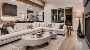 Una sala de estar moderna con un sofá modular, una mesa de centro redonda y un ventanal grande.