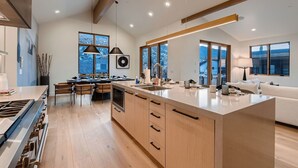 Una cocina moderna con una isla grande, armarios de madera y un comedor con sillas.