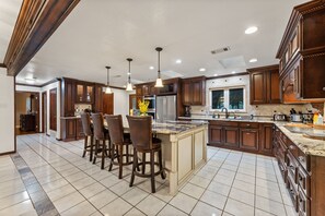 A spacious kitchen with dark wooden cabinets, a large island with bar stools, and modern appliances.