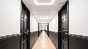 A long, narrow hallway with black doors on both sides and a tiled floor. - Parasasa Hotel Curacao (Willemstad)